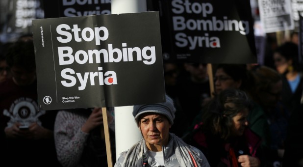Protesters hold placards during a demonstration against bombing Syria outside the Houses of Parliament in London, Britain.
