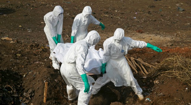 Health workers carry the body of a suspected Ebola victim for burial at a cemetery in Freetown, Sierra Leone, Dec. 21, 2014.