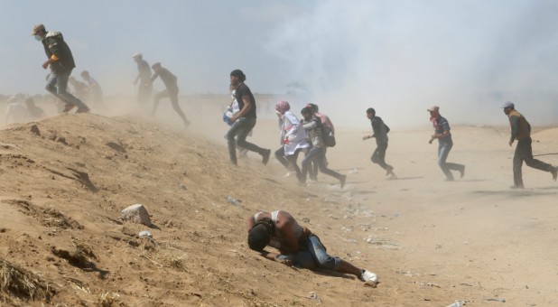 A Palestinian demonstrator reacts as others run from tear gas fired by Israeli forces during a protest.