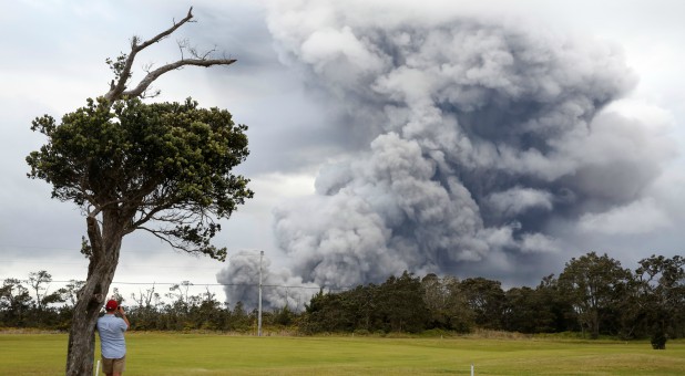 A man watches as ash erupts from the Halemaumau crater near the community of Volcano during ongoing eruptions of the Kilauea Volcano in Hawaii.