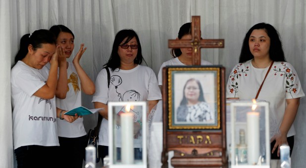 Relatives of victims of suicide attacks on three churches pray beside a coffin of Martha Djumani, who died at a church during Sunday's attack in Surabaya, Indonesia.