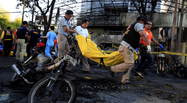 Paramedics remove a body near burned motorcycles following a blast at the Pentecost Church Central Surabaya (GPPS), in Surabaya, Indonesia.