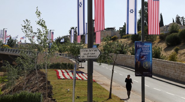 A woman walks next to a road sign directing to the U.S. Embassy, in the area of the U.S. consulate in Jerusalem.
