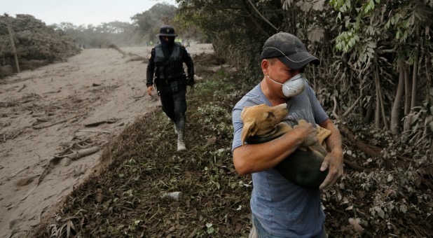 A resident carries his dog as he leaves an area affected by the eruption from Fuego volcano in the community of San Miguel Los Lotes in Escuintla, Guatemala.