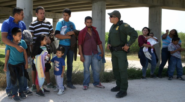 Border patrol agent Sergio Ramirez talks with immigrants who illegally crossed the border from Mexico into the U.S.