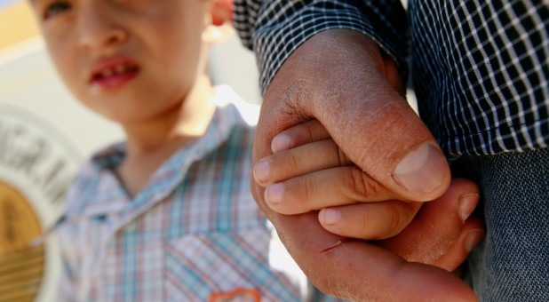 Salvadoran migrant Epigmenio Centeno holds the hand of his 3-year old son Steven Atonay outside the shelter House of the Migrant.