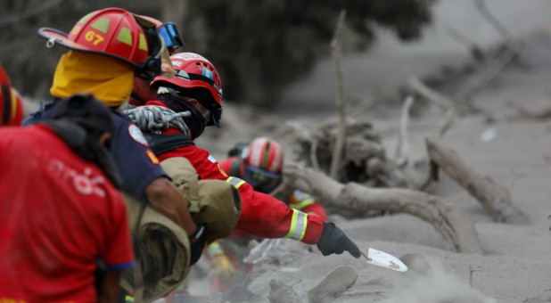 A firefighter shovels ashes while searching for bodies at an area affected by the eruption of the Fuego volcano in the community of San Miguel Los Lotes in Escuintla, Guatemala.