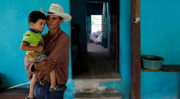 Jose Guardado, 42, a deportee from the U.S. carries his youngest son Neimar, 3.