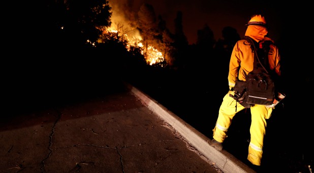 A firefighter watches the flames advance up a hill towards homes as crews battle the Carr Fire, west of Redding, California.