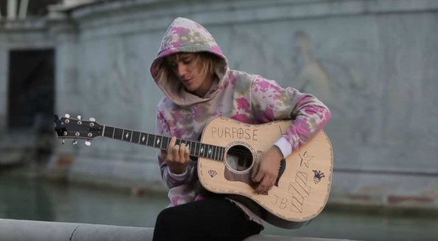 Justin Bieber plays the guitar outside Buckingham Palace.
