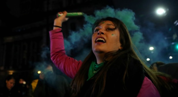 An abortion rights activist holds a flare outside the Congress after senators rejected a bill to legalize abortion, in Buenos Aires, Argentina.