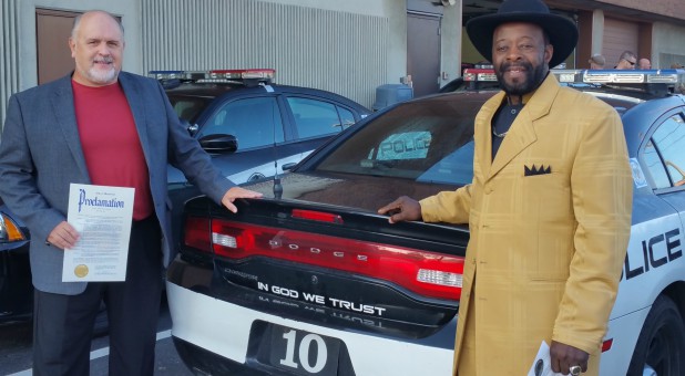 Pastors pose with police car with national motto for Clergy Appreciation Month in 2017.