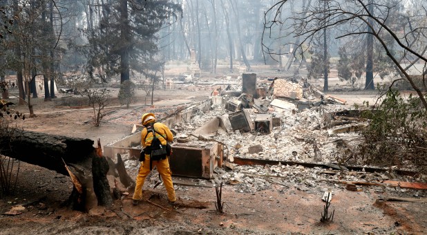 A firefighter extinguishes a hot spot in a neighborhood destroyed by the Camp Fire in Paradise, California.