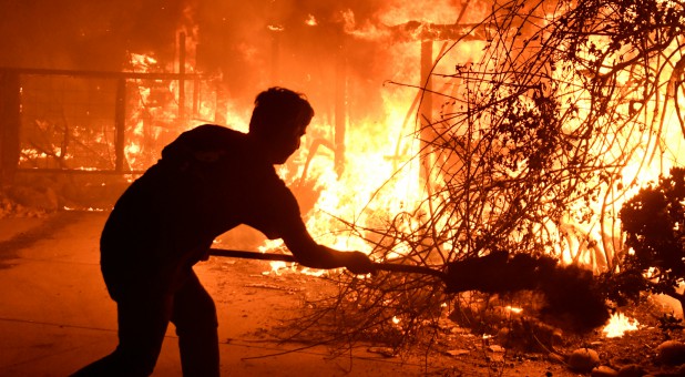 Homeowner Will Buckley uses a shovel with dirt to try to stop the flames from from destroying a neighbor's home during the Woolsey Fire in Malibu, California.