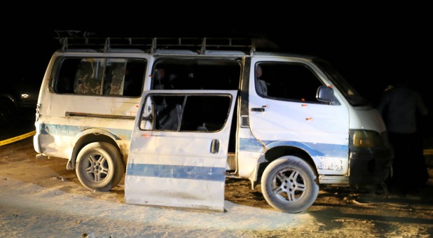 Policemen stand beside the microbus that carried Coptic Christians when gunmen opened fire in Menyia, Egypt.