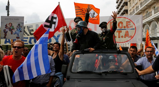 Demonstrators, dressed as Nazis, wave a Greek and a swastika flag as they ride in an open-top car in Syntagma Square in Athens as they protest against the visit of Germany's Chancellor Angela Merkel.