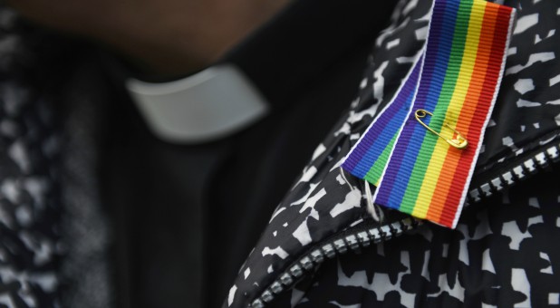 A priest wears a rainbow ribbon during a vigil against Anglican homophobia, outside the General Synod of the Church of England in London.