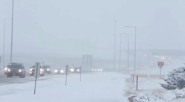 Cars move along a snow-covered road in Denver.