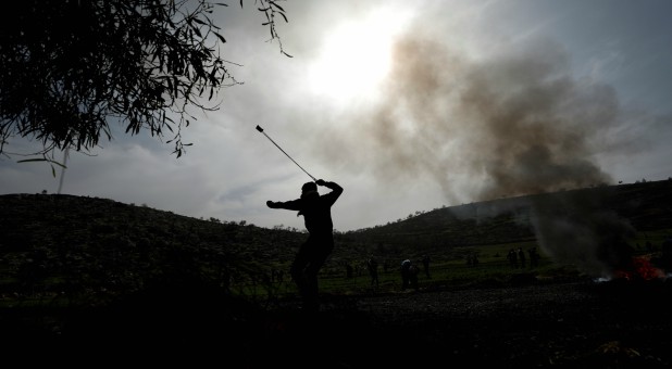 A Palestinian uses a sling to hurl stones at Israeli forces during clashes in al-Mughayer village near Ramallah, in the Israeli-occupied West Bank.