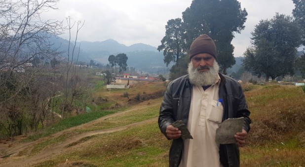 Fida Hussain, 46, holds what he believes to be fragments of payload released by the Indian military aircrafts, in Jaba village, Pakistan.