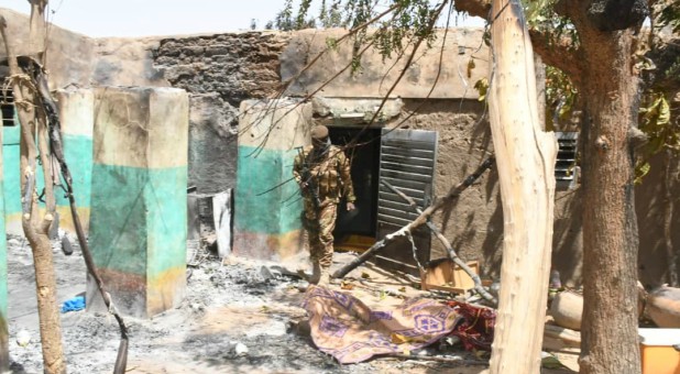A soldier walks amid the damage after an attack by gunmen on Fulani herders.