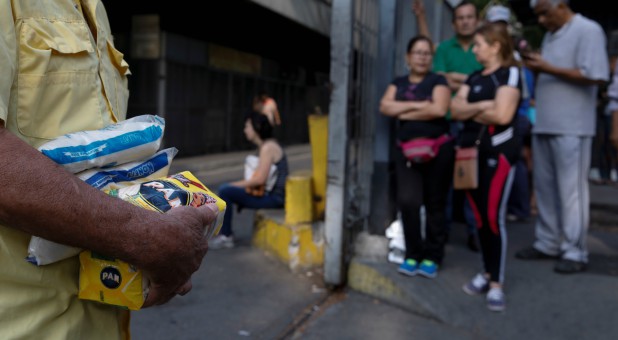 A man carrying packages of corn flour and sugar walks out from a supermarket during a blackout in Caracas, Venezuela.