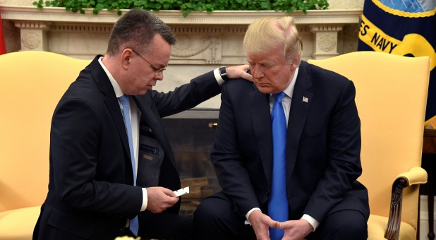 U.S. President Donald Trump closes his eyes in prayer along with Pastor Andrew Brunson.