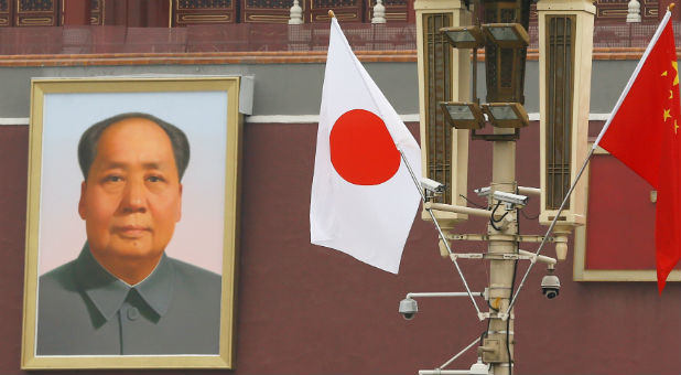 Chinese and Japanese flags flutter in front of a portrait of former Chinese chairman Mao Zedong at the Tiananmen Gate.