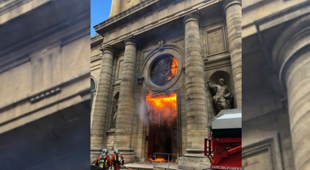 Members of the fire brigade run as a Saint-Sulpice church is seen on fire in Paris, France.