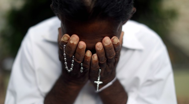 A person mourns at the grave of a victim, two days after a string of suicide bomb attacks on churches and luxury hotels across the island on Easter Sunday.
