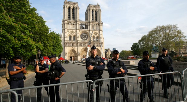Police officers stand behind the security barriers in front of Notre Dame Cathedral.