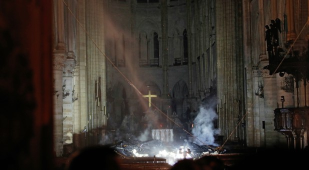 Smoke rises around the altar in front of the cross inside the Notre Dame Cathedral as a fire continues to burn in Paris, France.
