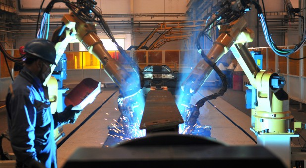 A worker stands next to robotic arms welding pump truck part at a factory of the Foton Loxa Heavy Machinery Co in Zhangjiakou, Hebei province, China.