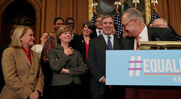 U.S. Senate Democratic leader Chuck Schumer, right, credits U.S. Senator Tammy Baldwin, D-Wis., left, for an LGBTQ cheer as they gather to announce the introduction of the Equality Act.
