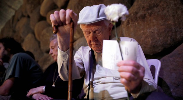 A Holocaust survivor holds flowers as he visits the Yad Vashem World Holocaust Remembrance Center as Israel mark the annual Israeli Holocaust Remembrance Day.