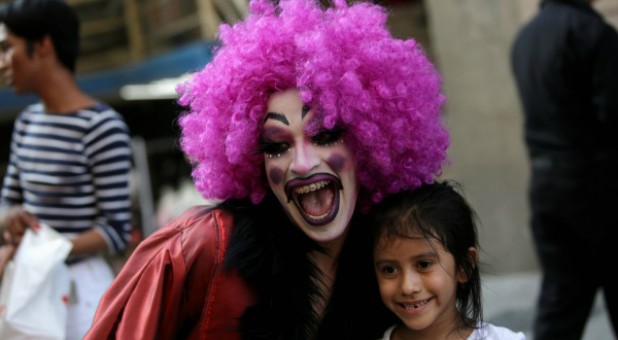 A participant dressed in drag poses for a picture with a child during the