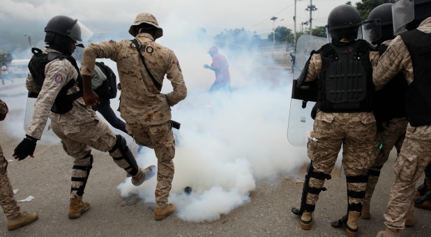 Haitian National Police (PNH) officers kick a tear gas canister during a protest outside of the Legislative Palace in Port-au-Prince.