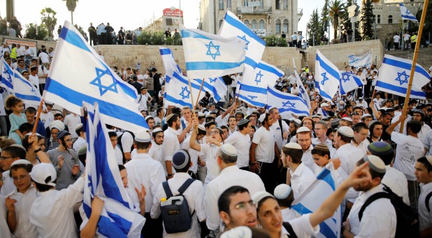 Jewish youth wave Israeli flags as they participate in a march marking