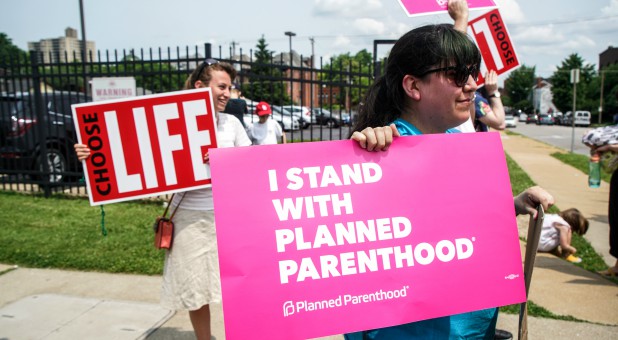 Pro-choice and pro-life protesters stand outside of Planned Parenthood.