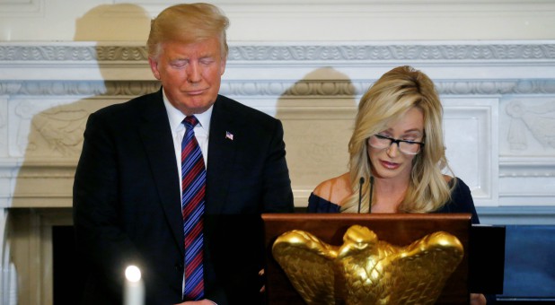 U.S. President Donald Trump closes his eyes as Pastor Paula White leads a prayer at a dinner hosted by the Trumps to honor evangelical leadership.