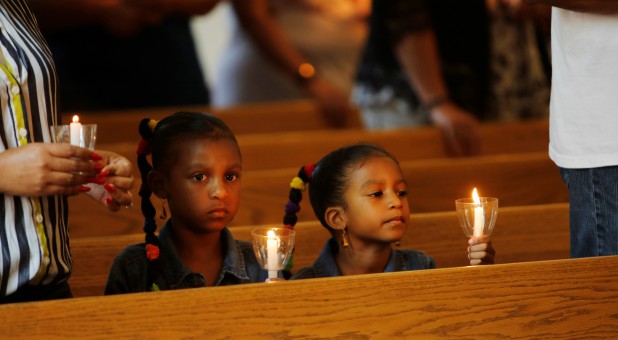 Madison Rochard, 6, and her sister Morgan, 5, hold candles at a prayer vigil for the victims of a Friday shooting incident in Virginia Beach.