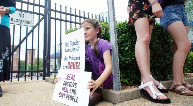 A young anti-abortion rights activist sits behind her signs at a rally in front of the Planned Parenthood in St. Louis, Missouri.