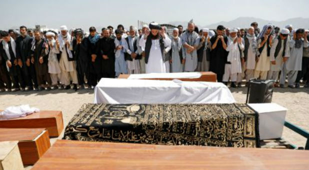 Afghan men offer funeral prayers over the coffins of the victims of a blast in a wedding in Kabul.