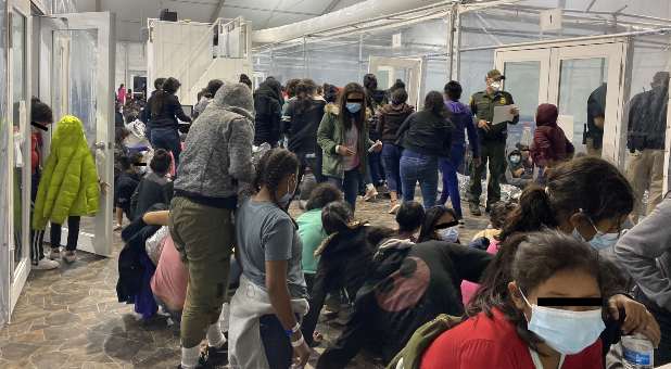 Migrants crowd a room with walls of plastic sheeting at the U.S. Customs and Border Protection temporary processing center in Donna, Texas, U.S. in a recent photograph released March 22, 2021. Office of Congressman Henry Cuellar (TX-28).
