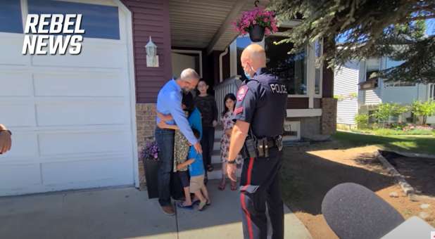 Pastor Tim Stephens hugging his children before being arrested outside his Alberta, Canada, home.