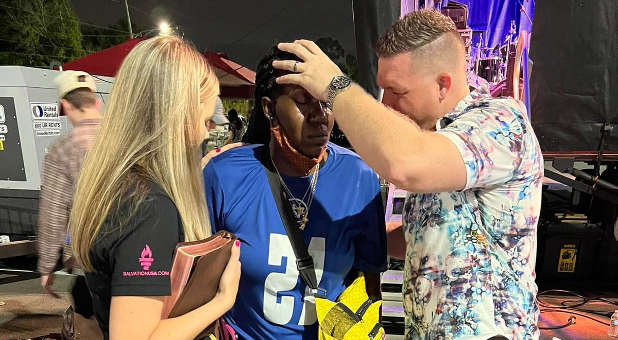 Evangelist Chris Mikkelson (R) and his wife, Amanda (L), pray for a woman on stage during the first night of this weekend's Salvation USA Good News Gospel Crusade in Orlando, Florida.