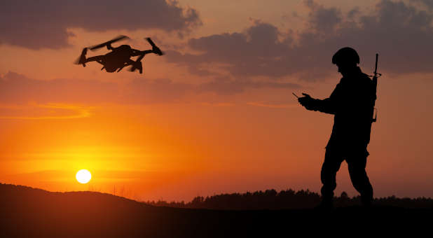 Soldier operating a drone via remote laptop.