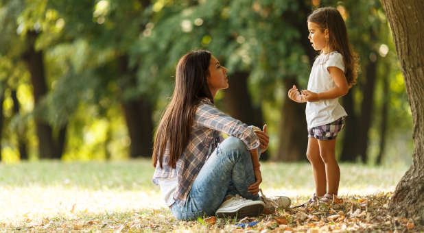 Mother teaching her daughter in a park.
