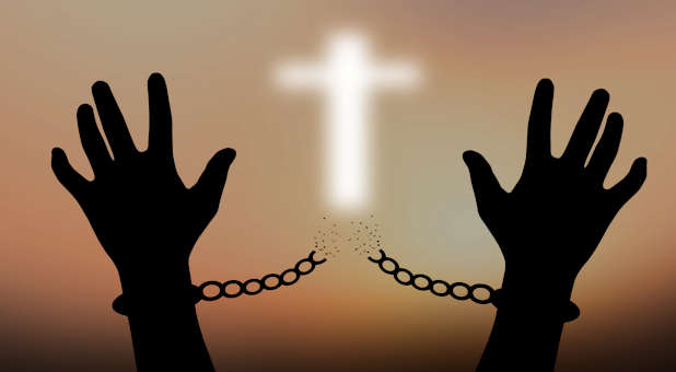 The cross of Jesus breaking chains holding people captive.