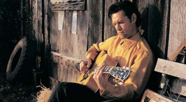 Young Randy Travis playing his guitar.